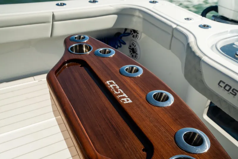 Slide: The Image of 2025 Costa Custom Boats 34, featuring a sleek wooden rod holder on deck. - 7