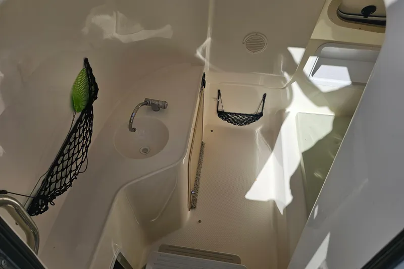Slide: The Image of Interior of a 2006 Hurricane SunDeck 260 OB boat, featuring a compact sink and storage nets. - 16