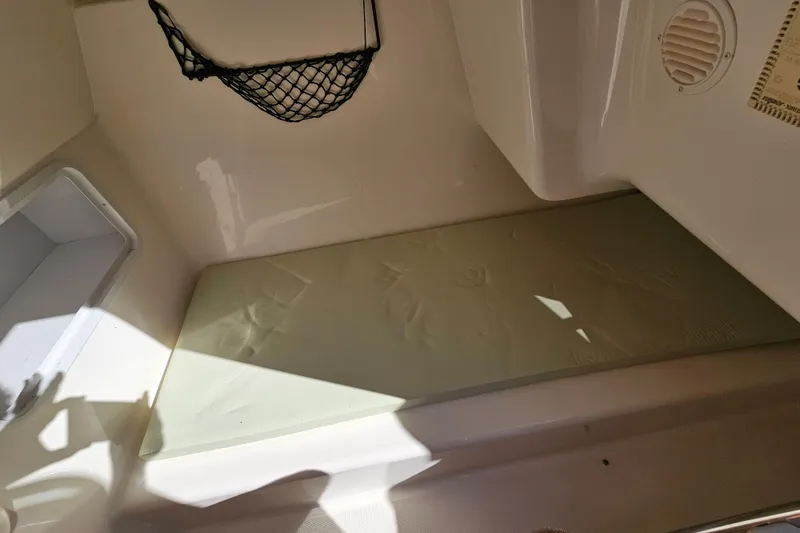 Slide: The Image of 2006 Hurricane SunDeck 260 OB interior with cushioned seating and storage compartment. - 17