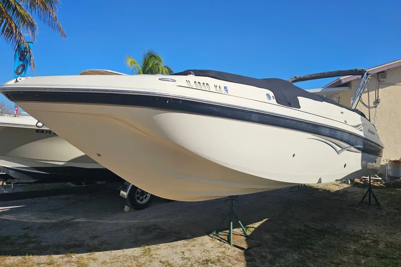 Slide: The Image of 2006 Hurricane SunDeck 260 OB boat on stands, under clear blue sky. - 3