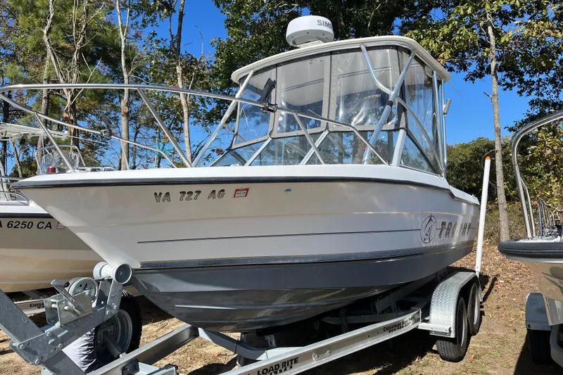 The Image of 1992 Bayliner 2000 Trophy boat on trailer, parked outdoors with trees in background. - 0