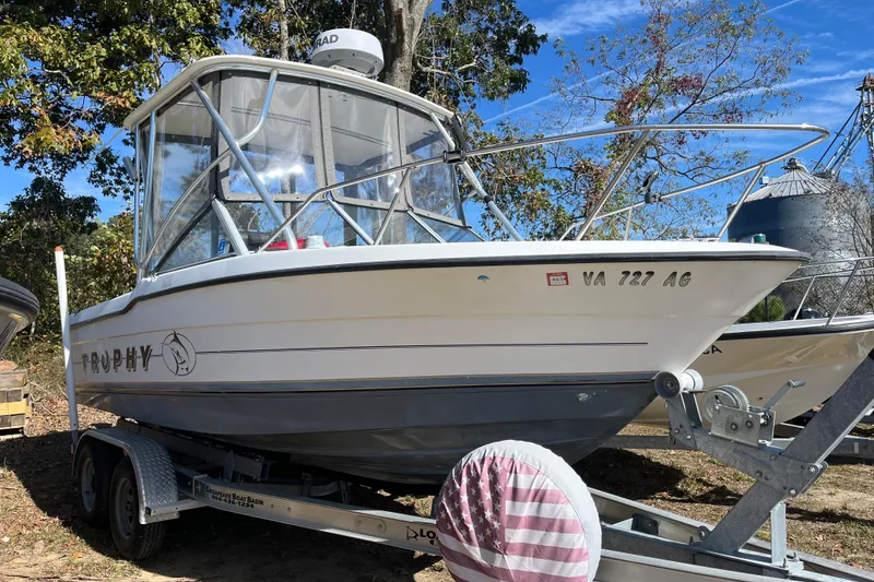 Slide: The Image of 1992 Bayliner Trophy 2000 boat on trailer, parked outdoors with trees in background. - 17