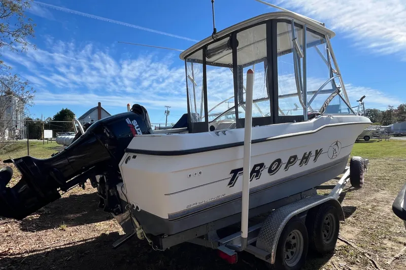 Slide: The Image of 1992 Bayliner Trophy 2000 boat on trailer, featuring Suzuki outboard motor, under clear blue sky. - 18
