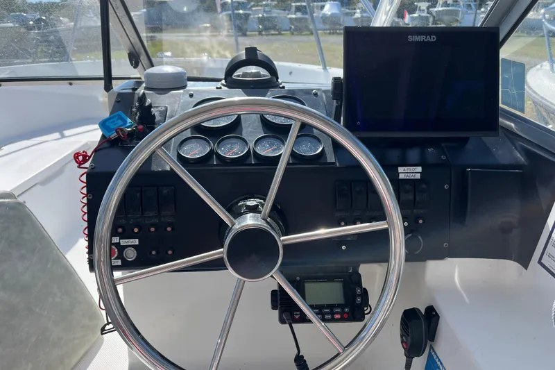Slide: The Image of 1992 Bayliner Trophy 2000 helm with steering wheel, gauges, and Simrad display. - 2