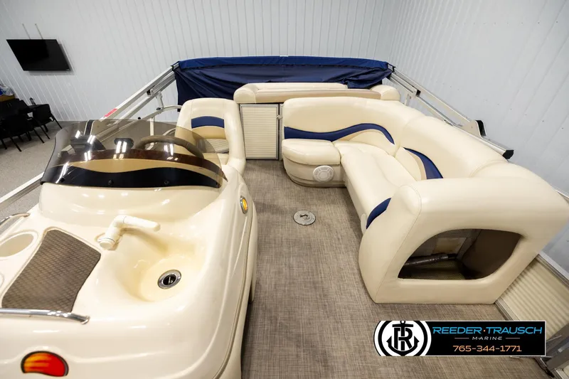 Slide: The Image of 2008 Sun Tracker Party Barge 24 interior with beige seating and helm, showcased indoors. - 13