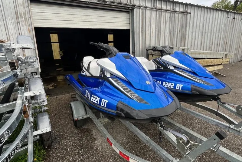 The Image of 2017 Yamaha WaveRunner VX Limited jet skis on trailers outside a garage. - 1