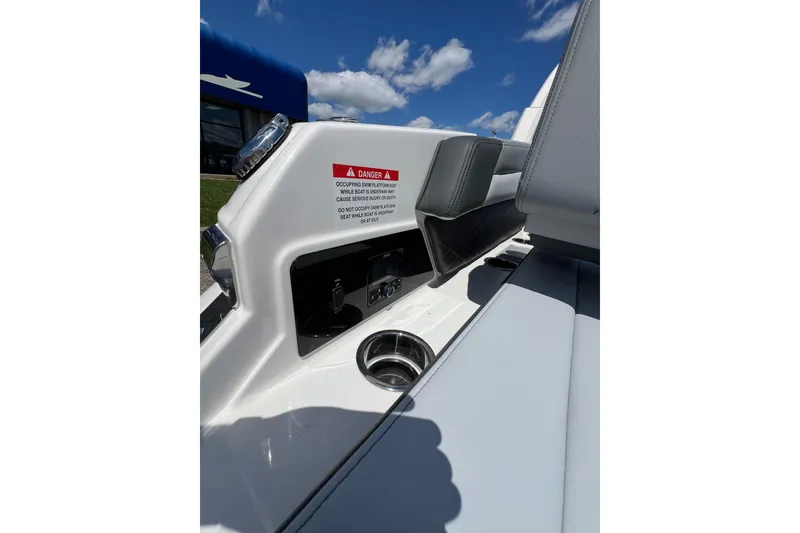 Slide: The Image of 2026 Chaparral SSX 6 boat interior with warning label and cup holder under blue sky. - 17