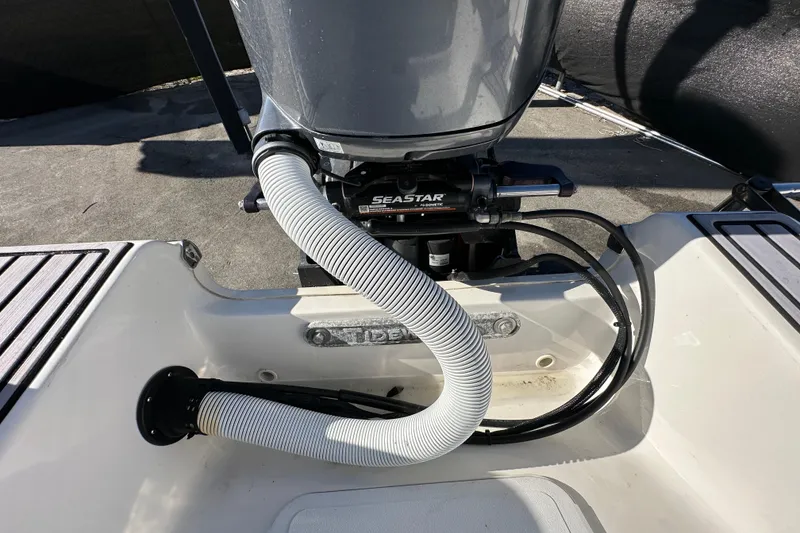 Slide: The Image of 2023 Tidewater 210 CC Adventure boat interior with seating and console, under a clear blue sky. - 38