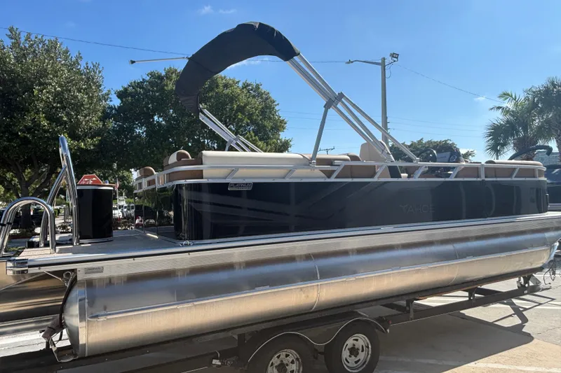 Slide: The Image of 2026 Tahoe Pontoon Sport 85 Quad Lounge on trailer, sunny day, trees in background. - 4