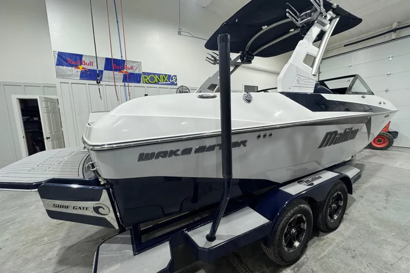 Slide: The Image of 2019 Malibu Wakesetter 21 MLX boat in a garage, featuring a sleek design and trailer. - 5