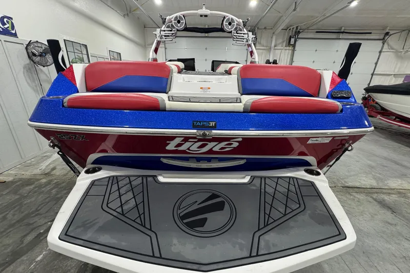 Slide: The Image of 2021 Tigé 25ZX boat in showroom, red and white design, on trailer. - 16