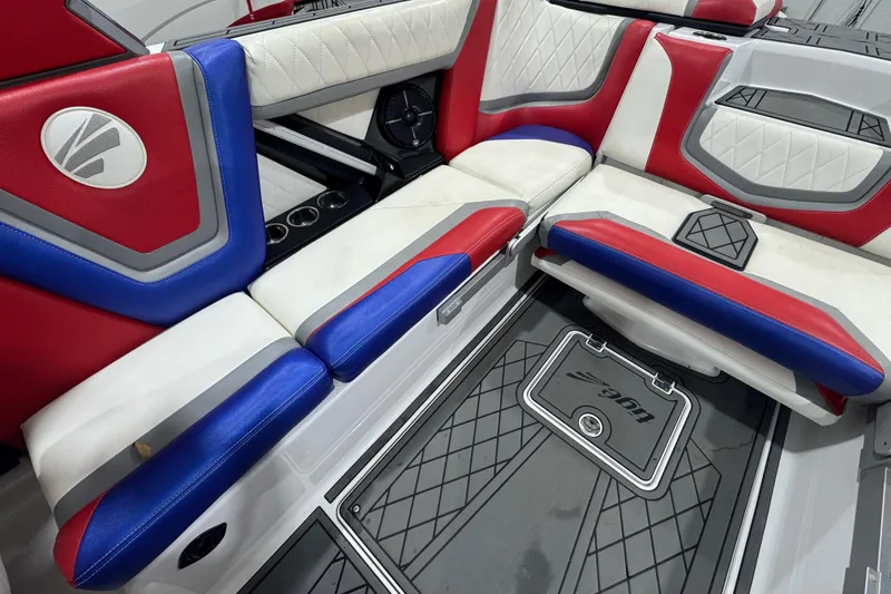 Slide: The Image of 2021 Tigé 25ZX boat interior with red, white, and blue seating in showroom. - 23