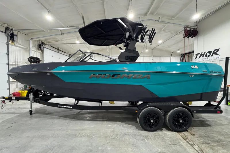 The Image of 2026 Moomba Tykon boat in a garage, featuring a sleek teal and black design. - 1