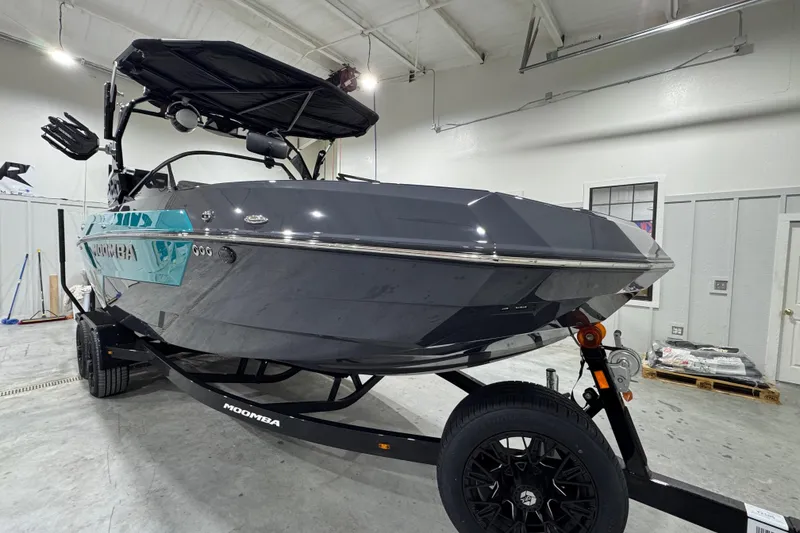 Slide: The Image of 2026 Moomba Tykon boat in a garage, sleek design, black and teal accents. - 7