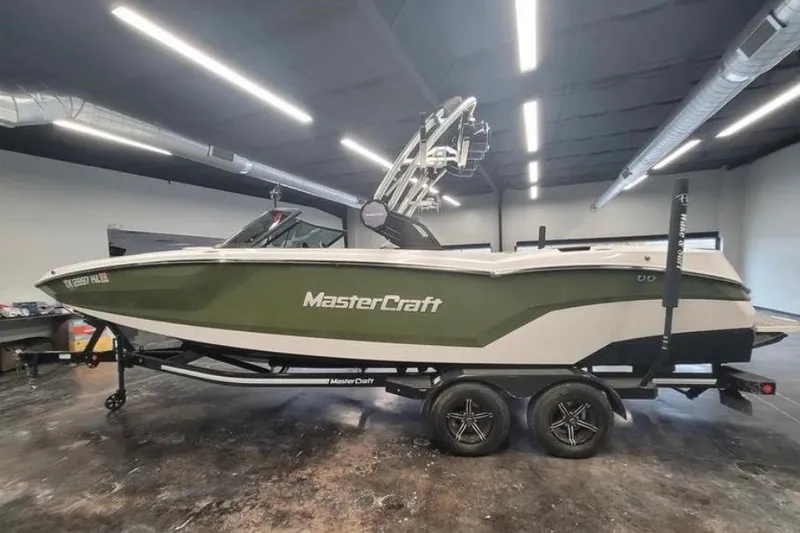 Slide: The Image of 2022 MasterCraft NXT24 boat in showroom, green and white design, on trailer. - 6