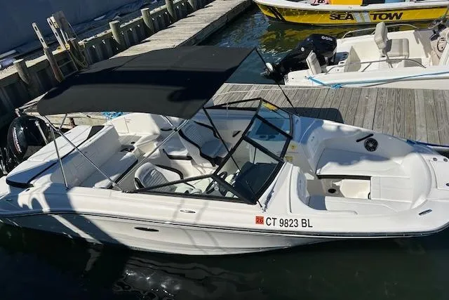 Slide: The Image of 2023 Sea Ray 21 SPX OB boat docked with black canopy and white seating. - 2