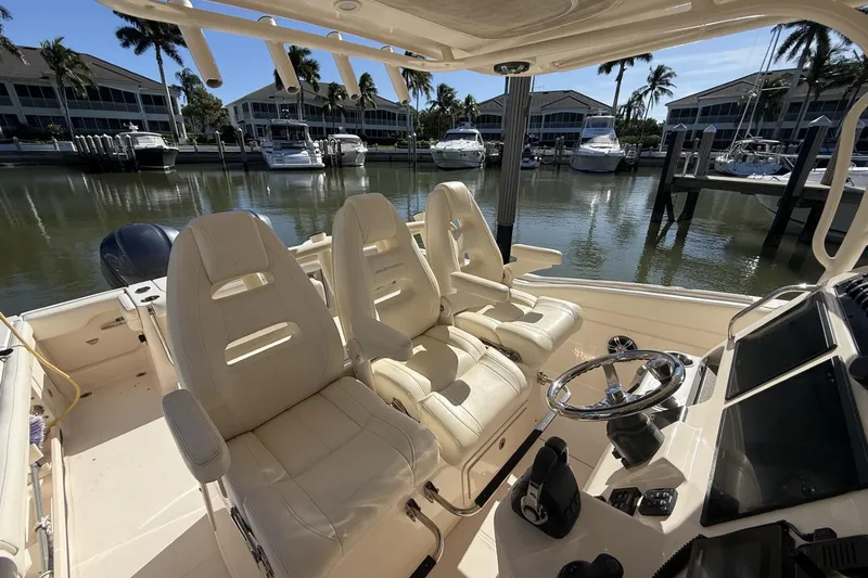 Slide: The Image of 2020 Grady-White Canyon 326 boat interior with helm and seating, docked near waterfront homes. - 18