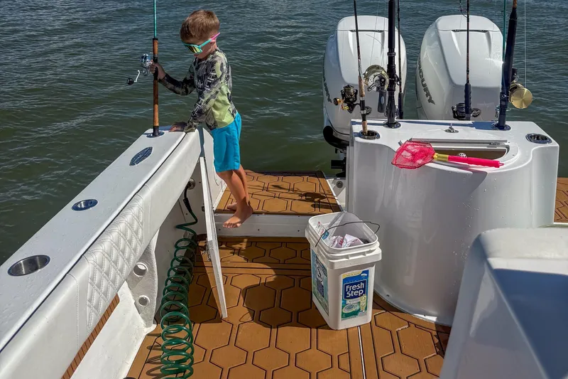 Slide: The Image of Child fishing on 2024 Ocean Runner 34 Center Console boat, with fishing gear and engines visible. - 13