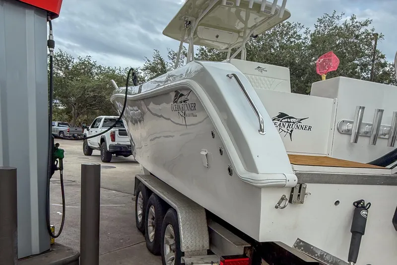 Slide: The Image of 2024 Ocean Runner 34 Center Console boat on trailer at gas station. - 14