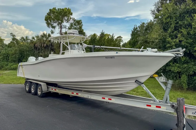 Slide: The Image of 2024 Ocean Runner 34 Center Console boat on a trailer, surrounded by lush greenery. - 2