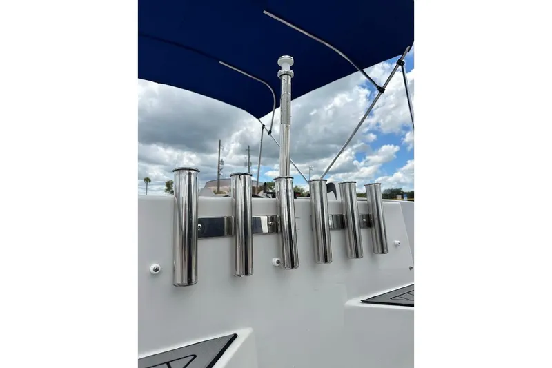 Slide: The Image of 2023 Starcraft SVX 171 OB boat with rod holders and blue canopy under cloudy sky. - 19