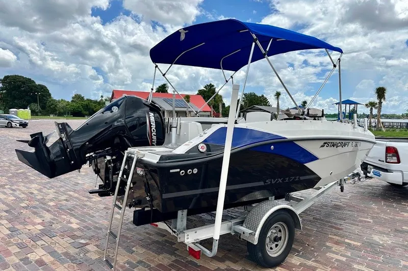 Slide: The Image of 2023 Starcraft SVX 171 OB boat on trailer with blue canopy and Mercury outboard motor. - 3