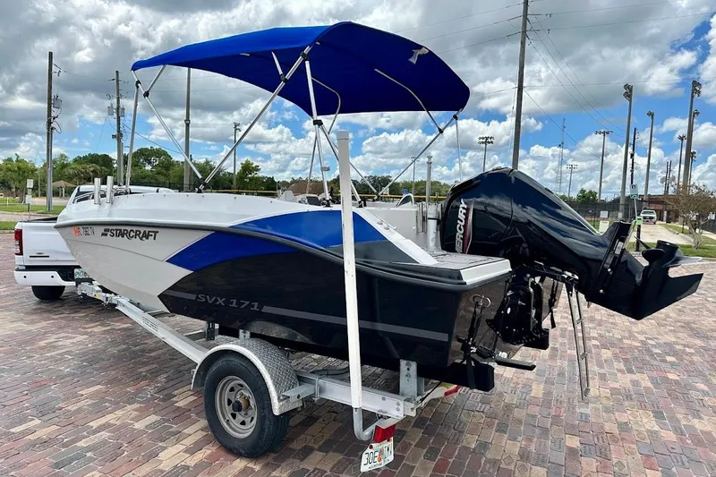 Slide: The Image of 2023 Starcraft SVX 171 OB boat on trailer, blue canopy, parked outdoors. - 4