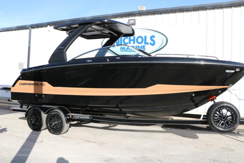 The Image of 2025 Chaparral 2870 SSX boat on trailer, black and tan design, parked at Nichols Marine. - 0