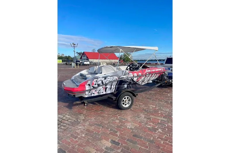 Slide: The Image of 2017 Scarab 165 HO boat with custom graphics, parked on a brick surface under a clear sky. - 1