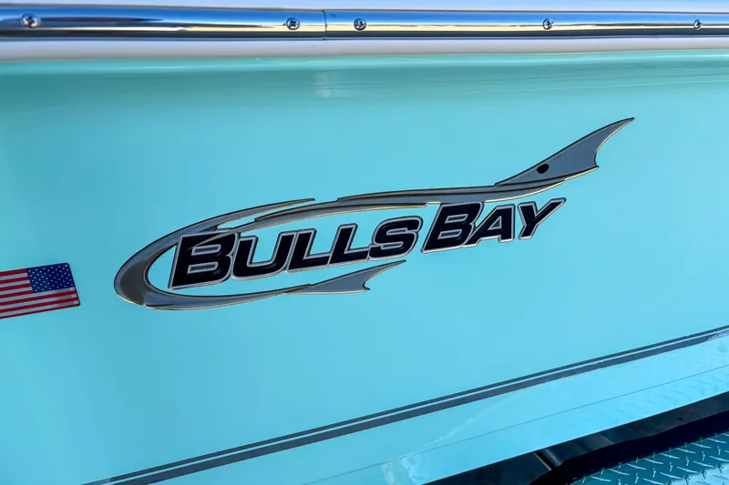 Slide: The Image of 2026 Bulls Bay 2200 XS boat logo on light blue hull with American flag decal. - 2