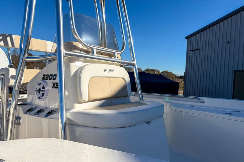 Slide: The Image of 2026 Bulls Bay 2200 XS boat interior with seating and console, under clear blue sky. - 8