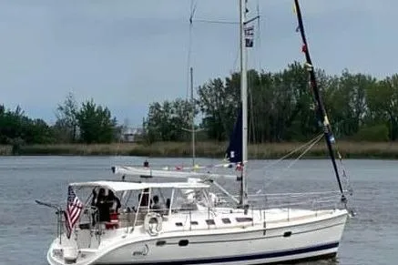 Slide: The Image of 2005 Hunter 46LE sailboat on calm water, featuring a sleek white design and American flag. - 1