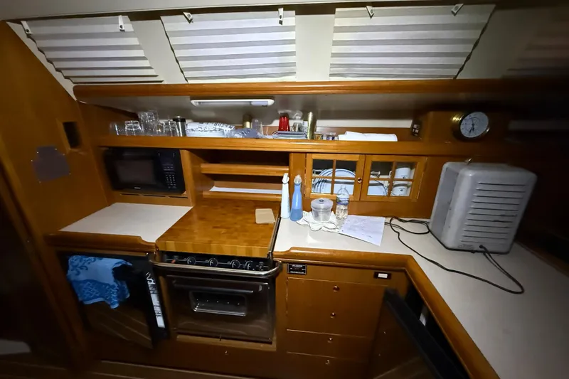 Slide: The Image of 2005 Hunter 46LE yacht kitchen with microwave, stove, and wooden cabinetry. - 16