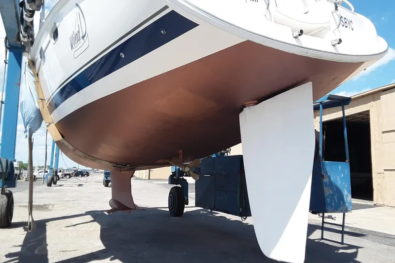 Slide: The Image of 2005 Hunter 46LE sailboat on dry dock, showcasing hull and rudder. - 7