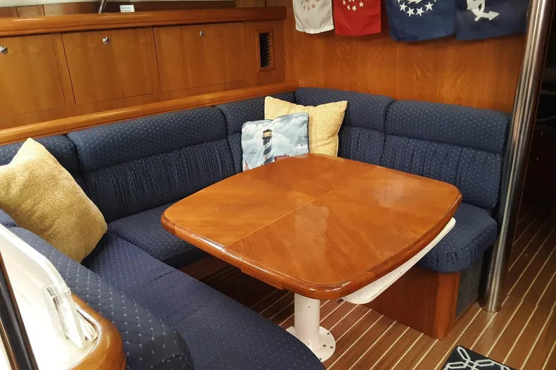 Slide: The Image of Cozy dining area in 2005 Hunter 46LE yacht with wooden table and blue cushioned seating. - 13