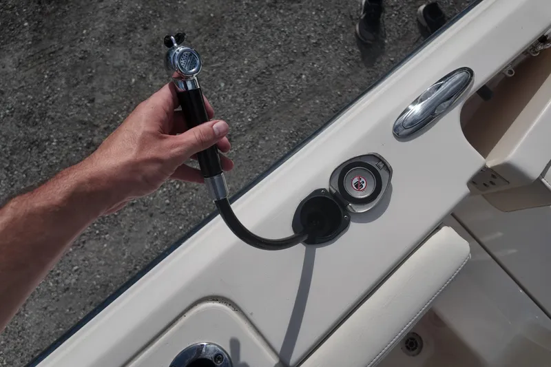 Slide: The Image of Hand holding a hose on a 2023 Grady White Fisherman 236 boat deck. - 19