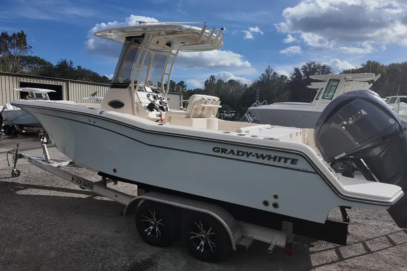 Slide: The Image of 2023 Grady-White Fisherman 236 boat on trailer, parked outdoors under a cloudy sky. - 3