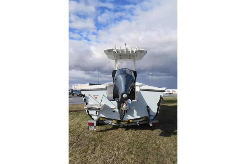 Slide: The Image of 2022 Parker 2300 Special Edition boat with outboard motor, parked on grass under cloudy sky. - 2