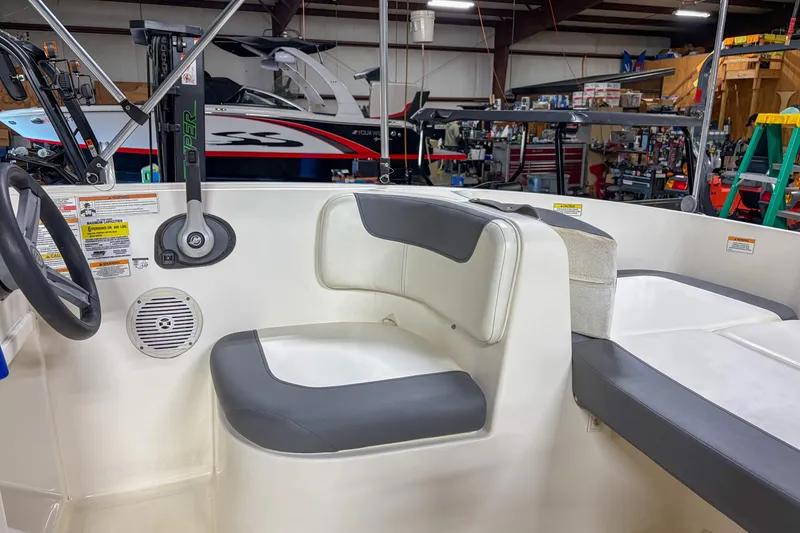 Slide: The Image of 2020 Bayliner Element E16 boat interior with seating and steering wheel in a workshop. - 4