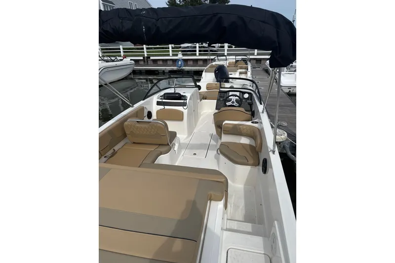 Slide: The Image of 2025 Bayliner VR6 Bowrider OB with tan seating and black canopy at dock. - 3