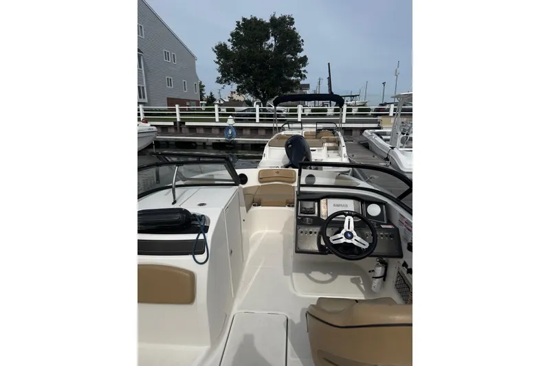 Slide: The Image of 2025 Bayliner VR6 Bowrider OB interior view at dock, showcasing steering and seating area. - 6