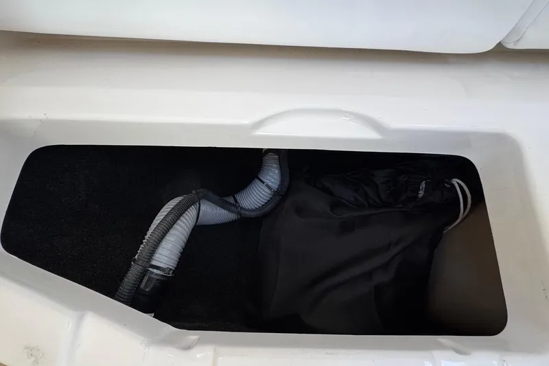 Slide: The Image of Storage compartment in 2026 Regal 33 XO boat with hoses and black bag. - 103