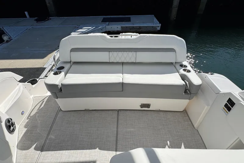 Slide: The Image of 2026 Regal 33 XO boat interior with cushioned seating and cup holders by the water. - 35
