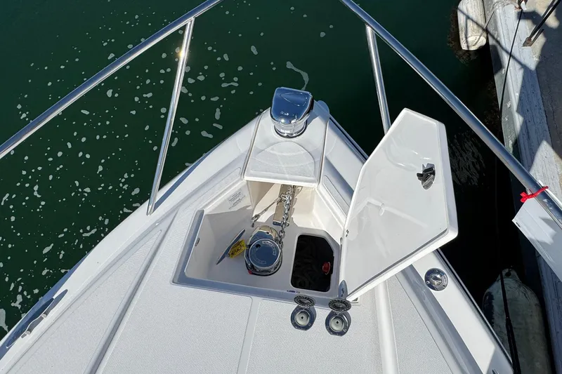 Slide: The Image of Bow of 2026 Regal 33 XO boat with anchor compartment open, docked on calm water. - 67
