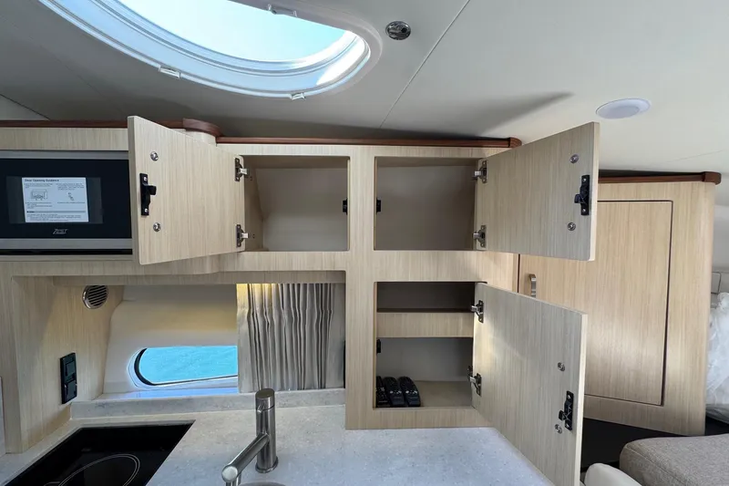 Slide: The Image of Interior of 2026 Regal 33 XO yacht with open wooden cabinets and modern kitchen features. - 83