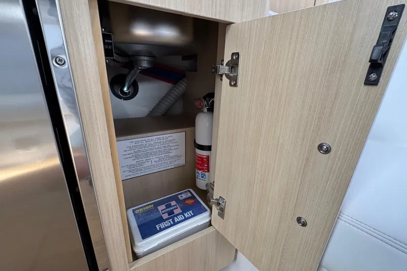 Slide: The Image of Open cabinet on Regal 33 XO 2026 boat with first aid kit and fire extinguisher. - 88