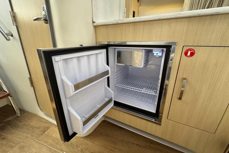 Slide: The Image of Open mini fridge in 2026 Regal 33 XO boat interior, showcasing storage space. - 89