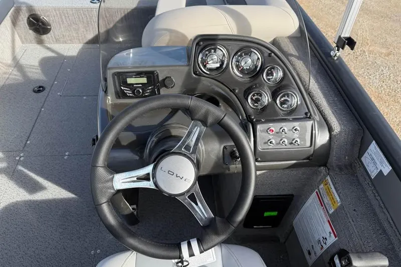 Slide: The Image of 2026 Lowe Sport Deck 224 boat dashboard with steering wheel and control gauges. - 10