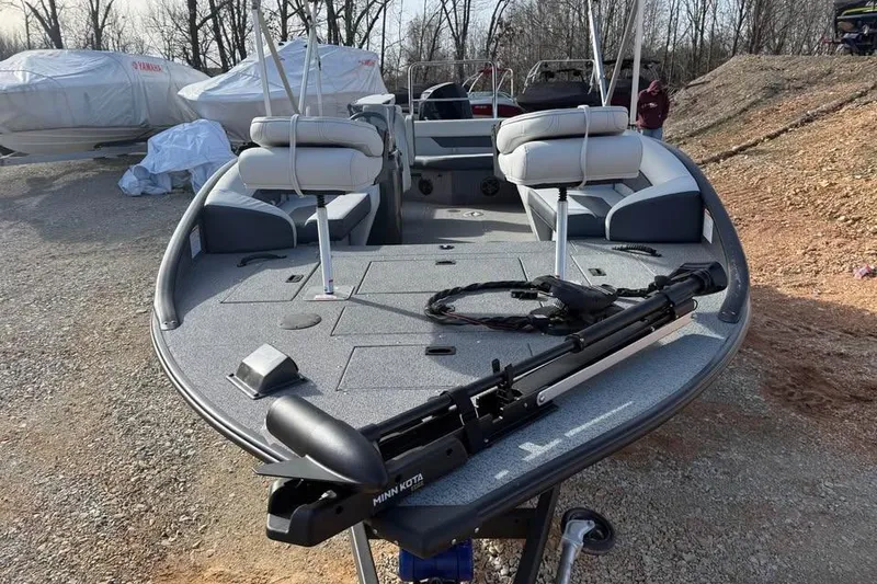 Slide: The Image of 2026 Lowe Sport Deck 224 boat with seating and trolling motor, parked on gravel. - 2