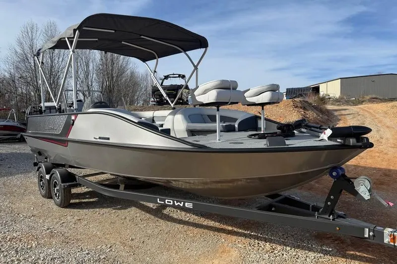 Slide: The Image of 2026 Lowe Sport Deck 224 boat with canopy on trailer, parked outdoors. - 3